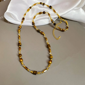 Détail des perles en oeil de tigre, cristaux facettés et chaîne dorée du collier vintage