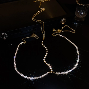 Catena per il corpo dorata di lusso con strass brillanti su sfondo scuro riflettente