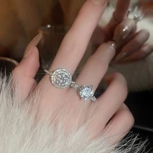 Close-up of elegant silver zircon rings set on a model with white plush sleeve background