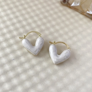 Vue détaillée de boucles d'oreilles en cœur avec texture marbre blanc et plaqué or