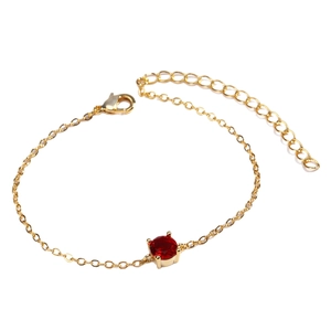 Elegant gold chain bracelet with round red gemstone featuring a secure lobster clasp