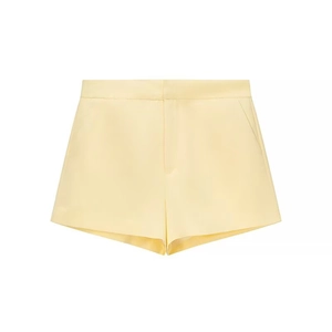 Detailed flat lay of pale yellow tailored shorts with high-quality fabric texture