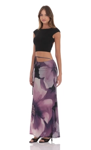 Detail of elegant two-piece set featuring black crop top and floral print maxi skirt
