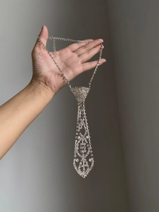 Macro detail of silver tie-shaped necklace with rhinestones and lobster clasp closure
