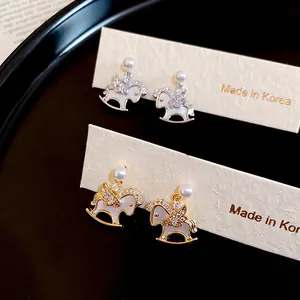 Elegant gold and silver rocking horse stud earrings with pearls and zircons on display