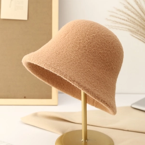 Elegant camel wool bucket hat displayed on a gold metal stand with a warm aesthetic