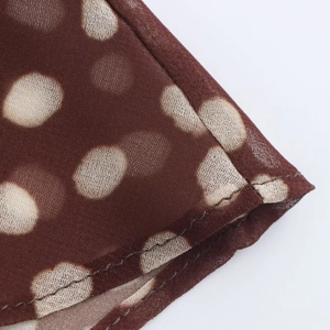 Macro detail of brown polka dot sheer mesh fabric with high-quality stitched hem finishes