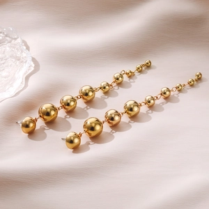 Minimalist gold metal ball drop earrings with gradient beads on pink silk background