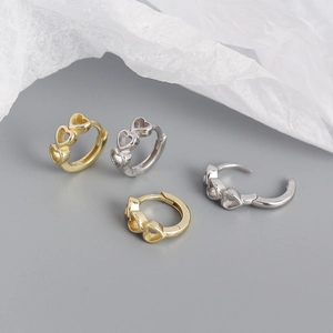 Detail of s925 silver heart hoop earrings in gold and silver finishes on white paper