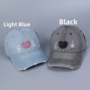 Close-up of distressed denim baseball caps with heart embroidery and vintage worn edges