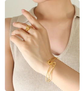 Detail of gold safety pin bracelet and ring set on model with soft lighting