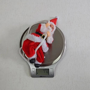 Detail view of a climbing Santa Claus figurine ornament being weighed on a scale