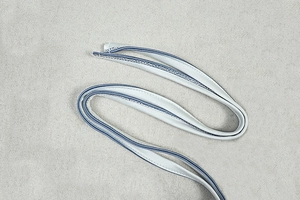 Close-up of light gray striped fabric shoulder strap with blue trim and detailed stitching