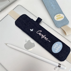 Detail of denim elastic band pen holder for iPad showing pink embroidered Carefree text