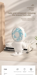 Close-up of a white astronaut mini fan with blue blades on a wooden desk with shadows