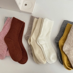 Flat lay of colorful thick wool socks in pink, brown, and cream on a white surface