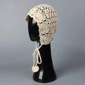 Détail d'un bonnet bohème au crochet ivoire avec glands en cœur et dentelle florale