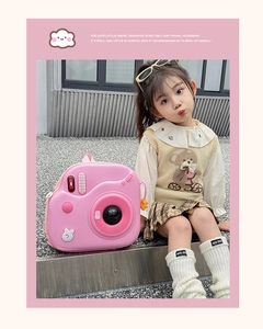 Zainetto rigido rosa a forma di fotocamera indossato da una modella all'aperto