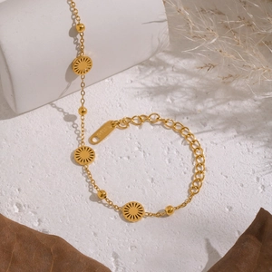 Detail of 18K gold-plated stainless steel sun charm bracelet on geometric props