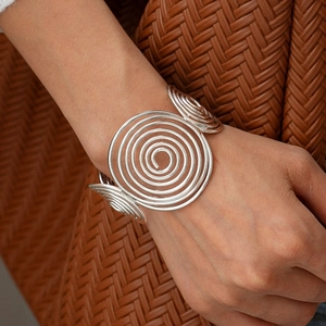 Macro shot of silver geometric spiral cuff bracelet with layered concentric circle design