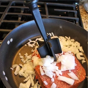 Close-up of a black meat chopper mashing ground meat and onions in a frying pan