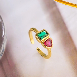 Detail of gold-plated ring with emerald-green rectangle and rose-red heart zircon stones