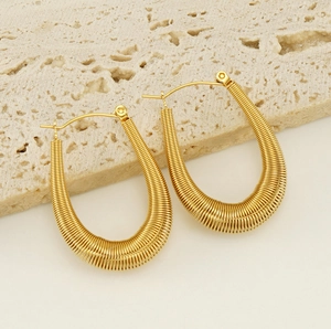 Macro shot of gold U-shaped earrings with textured spiral wrapping on a stone plate