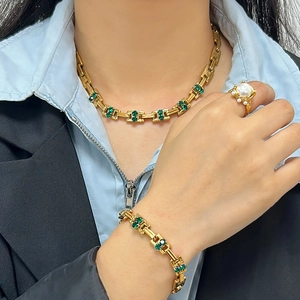 Vintage gold jewelry set with green gemstones and pearls including necklace and bracelet