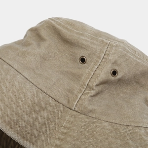 Close-up of khaki canvas bucket hat showing metal eyelets and detailed brim stitching