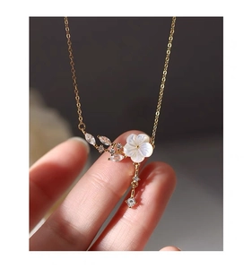 Macro shot of silver flower pendant with tassel and zircons on gold chain