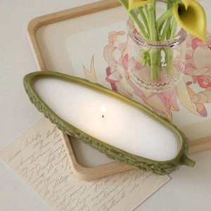 Detailopname van een brandende bittermeloenkaars met groene textuur op houten dienblad
