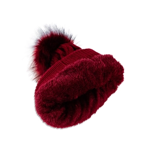 Close-up of cable knit beanie in burgundy with fluffy faux fur lining and plush pompom