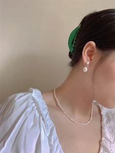 Close-up of model wearing small baroque freshwater pearl necklace and matching earrings