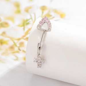 Silver navel piercing featuring a pink gemstone shield and a cross pendant on a white stand