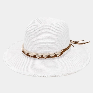 Detail of white straw sun hat featuring frayed edges and bohemian woven band decoration