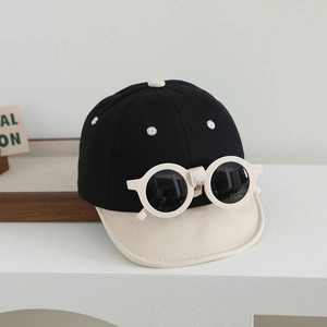 Détail de la casquette bébé avec broderie florale et lunettes de soleil rondes intégrées