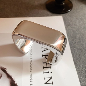Macro detail of silver mirrored wide open cuff bracelet with minimalist wavy design