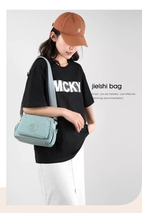 Detail of mint green waterproof nylon crossbody bag with multiple zipper layers and wide strap