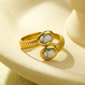 Detailed close-up of a gold ribbed open ring featuring two oval white marble stone inlays