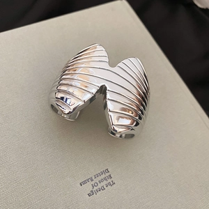 Macro view of wide minimalist silver bangle featuring wavy textures and a polished finish