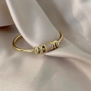 Close-up of golden adjustable cuff bracelet with pave zircons on beige silk fabric