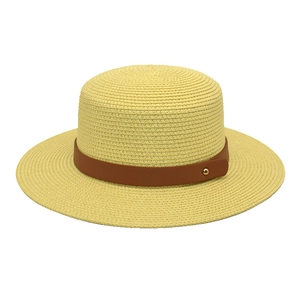 Detail of yellow straw boater hat featuring a brown leather band and gold metal rivet