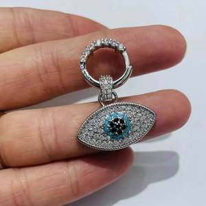Silberner Teufelsauge-Ohrring mit blauen Kristallen zwischen den Fingern gehalten