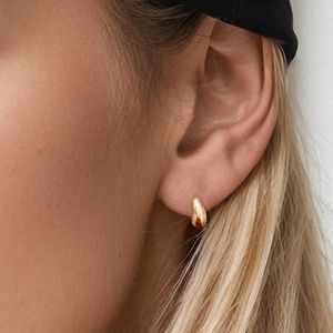 Macro shot of 18K gold water drop earrings showing sleek geometric design on ear