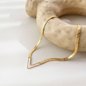 Detail of gold V-shaped pendant snake chain necklace with white mother-of-pearl inlay