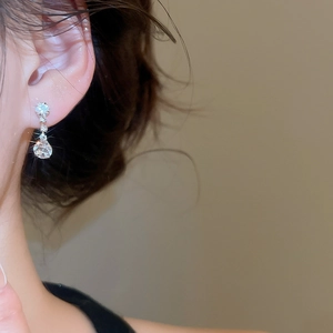 Close-up of elegant silver drop earrings with sparkling clear stones and a teardrop crystal