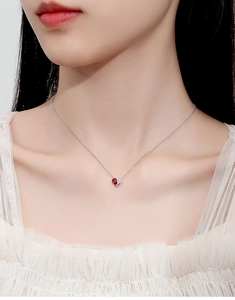 Close-up of S925 silver heart necklace with red gemstone and diamonds on model neck