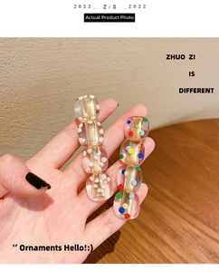 Macro detail of clear resin hair clips with colorful and white polka dots on gold metal