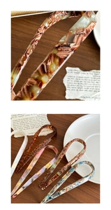 Detail of U-shaped acetate hair pins in tortoise and marble patterns on a vintage desk