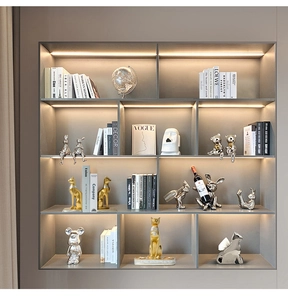 Modern Nordic golden animal sculptures and Moai statues displayed on a lighted shelf
